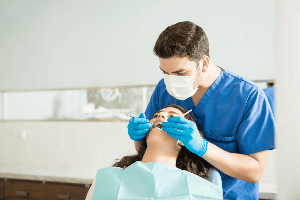 Dentist Examining Woman With Dental Carver At Clinic